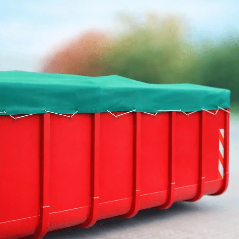 Großer roter Container, dessen Oberseite mit einer straff gespannten grünen Abdeckplane befestigt mit einer umlaufenden Gummileine gesichert ist