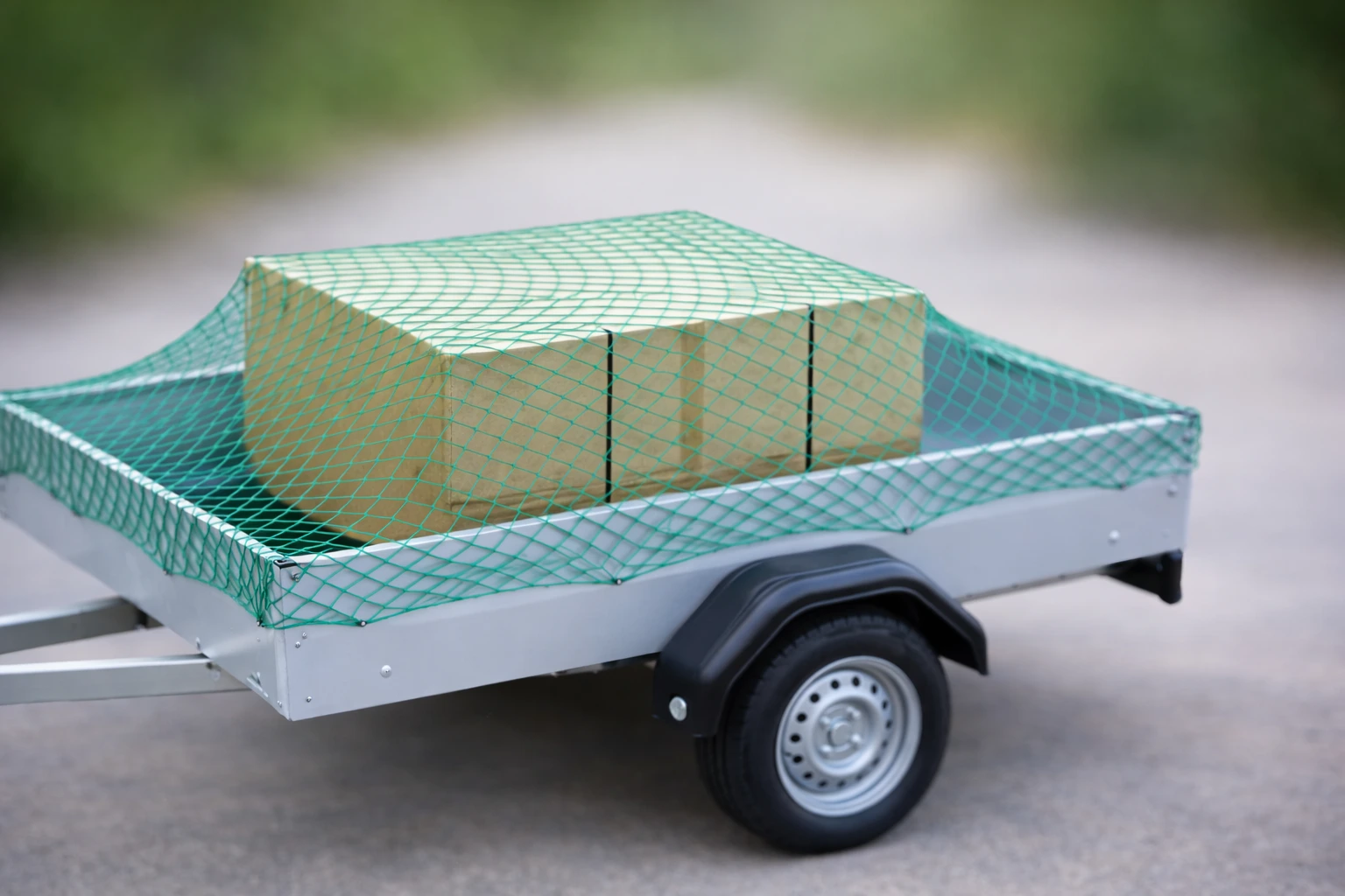 Grünes, geknotetes Abdecknetz aus PE über Kartons auf einem PKW-Anhänger gespannt
