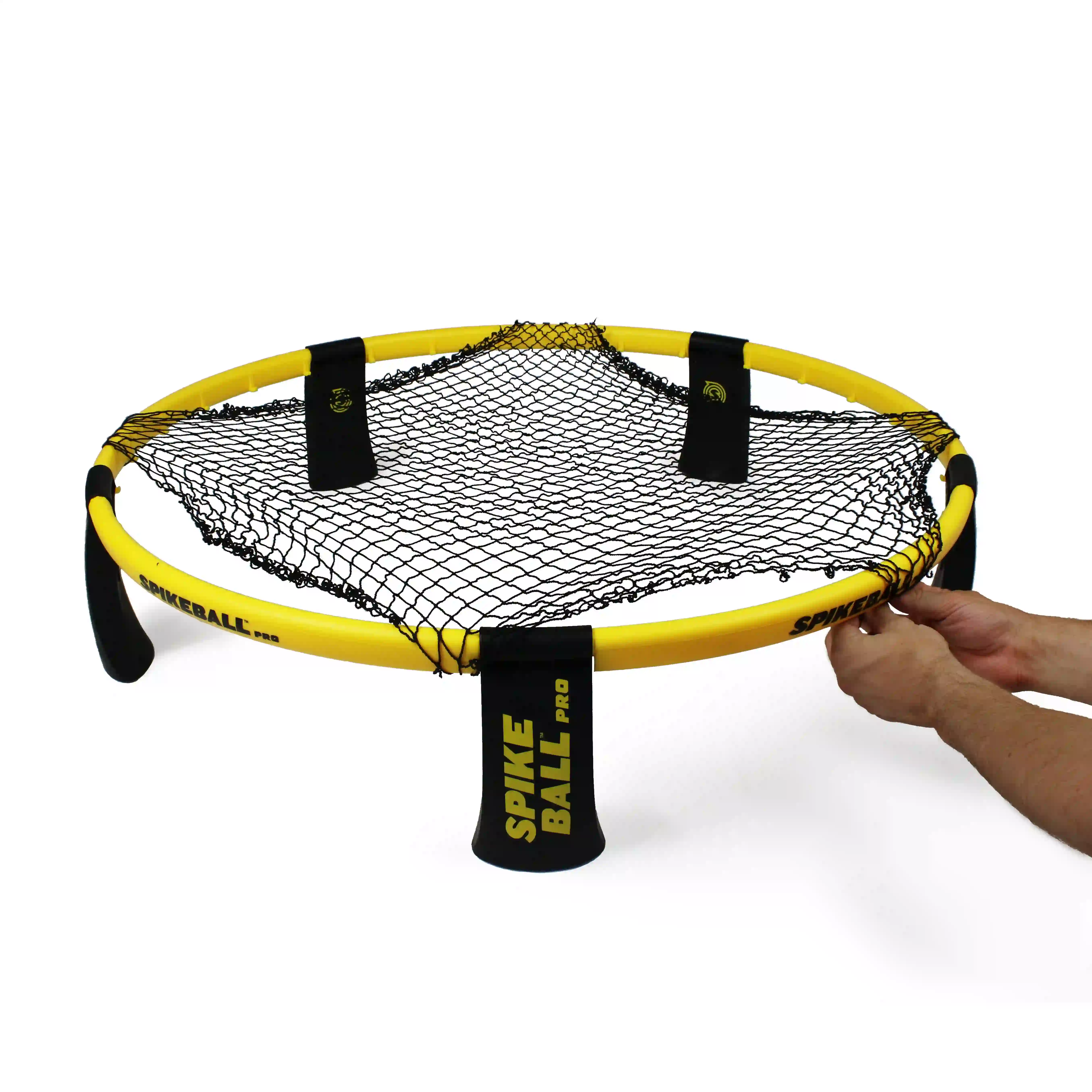 Hände spannen das Netz eines Spikeball‑Pro‑Sets, gelber Rahmen und schwarze Beine mit Aufschrift