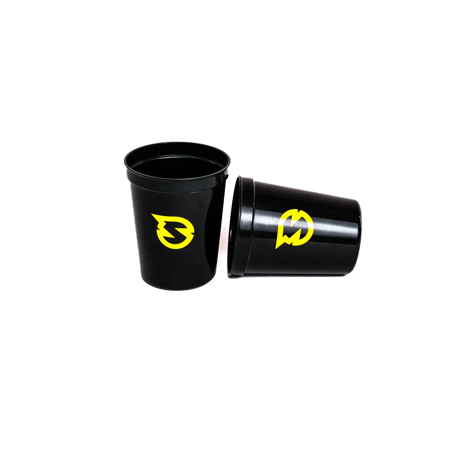 Zwei schwarze Spikeball Becher mit gelbem Logo, einer stehend und einer liegend auf weißem Hintergrund – robustes Zubehör für Outdoor‑Spiele und Freizeit